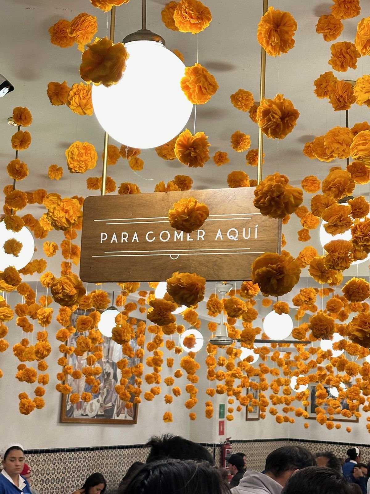 Para Comer Aquí sign surrounded by hanging cempasúchil marigolds